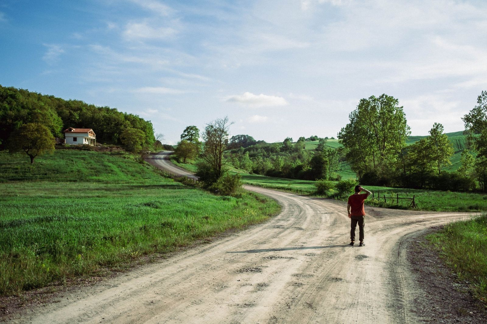 Un uomo fermo a un bivio su una strada di campagna